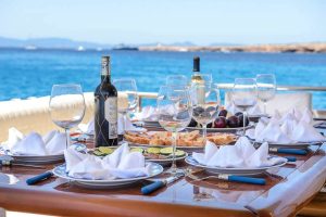 Elegant yacht dining setup with wine, glassware, and gourmet snacks overlooking turquoise Caribbean waters during a private Playa del Carmen yacht charter.