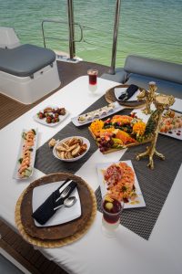 Gourmet seafood and fresh fruit platter served on a luxury yacht during a private snorkeling boat tour in Playa del Carmen, overlooking turquoise Caribbean water.