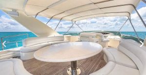 Luxury yacht interior with shaded seating area and round table overlooking turquoise Caribbean waters during a private Playa del Carmen yacht rental.