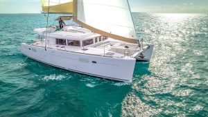Luxury white catamaran sailing in turquoise Caribbean waters near Playa del Carmen during a private boat rental tour.